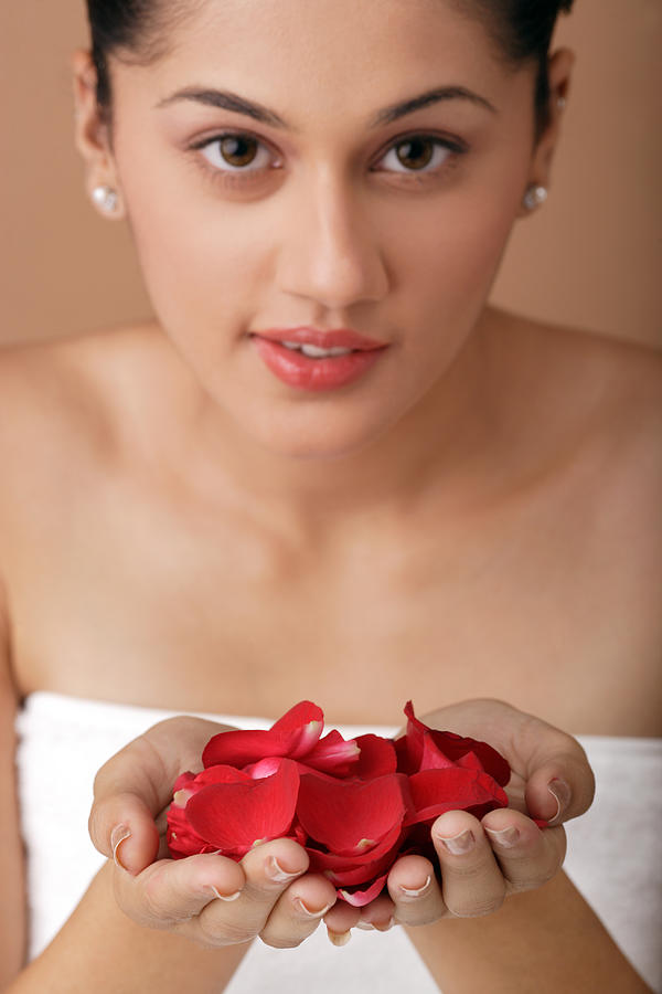 Young woman wrapped in towel holding rose petals Photograph by Visage