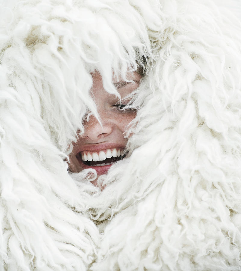Young woman wrapped in wool blanket, eyes closed, laughing, close-up Photograph by David Trood