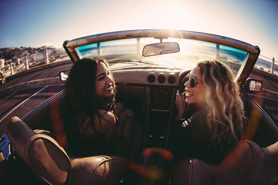 Young women having fun in convertible on seaside at sunset Photograph by Wundervisuals