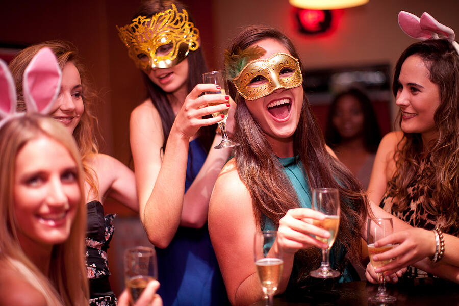Young women with drinks wearing masks at hen party Photograph by Zero Creatives