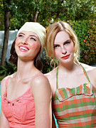 Closeup portrait of two women in vintage style bathing suits, sitting outside by a pool. Photograph by Dreampictures