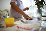 Boy finger painting at table Photograph by Caia Image