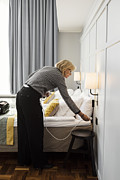 Businesswoman plugging cable by bed at hotel room Photograph by Maskot