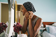 Smiling African American woman attaching earring Photograph by Peter Griffith