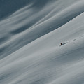 A lone skier descends a glacier. by Cavan Images