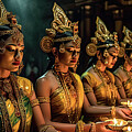 Group of Asian apsara dancers in green and yellow costumes holding candles  by Steve Estvanik
