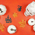 Halloween trick or treat flatlay on orange background with skull and pumpkins. by Milleflore Images