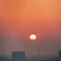 Passing plane over Amsterdam dives into the solar disc during sunset by Vaclav Sonnek